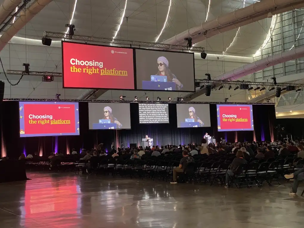 Georgi Ker presenting a lightning talk about PyladiesCon in front of large audience at PyCon US Georgi Ker presenting a lightning talk about PyLadiesCon at PyCon US